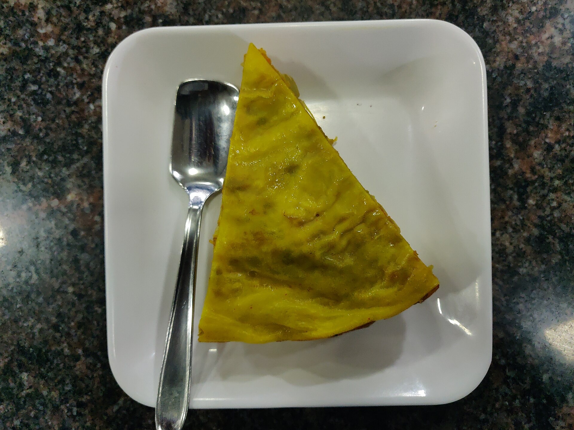 A wedge of sweet Chatti Pathiri showing the layered crepes and coconut-cashew filling.