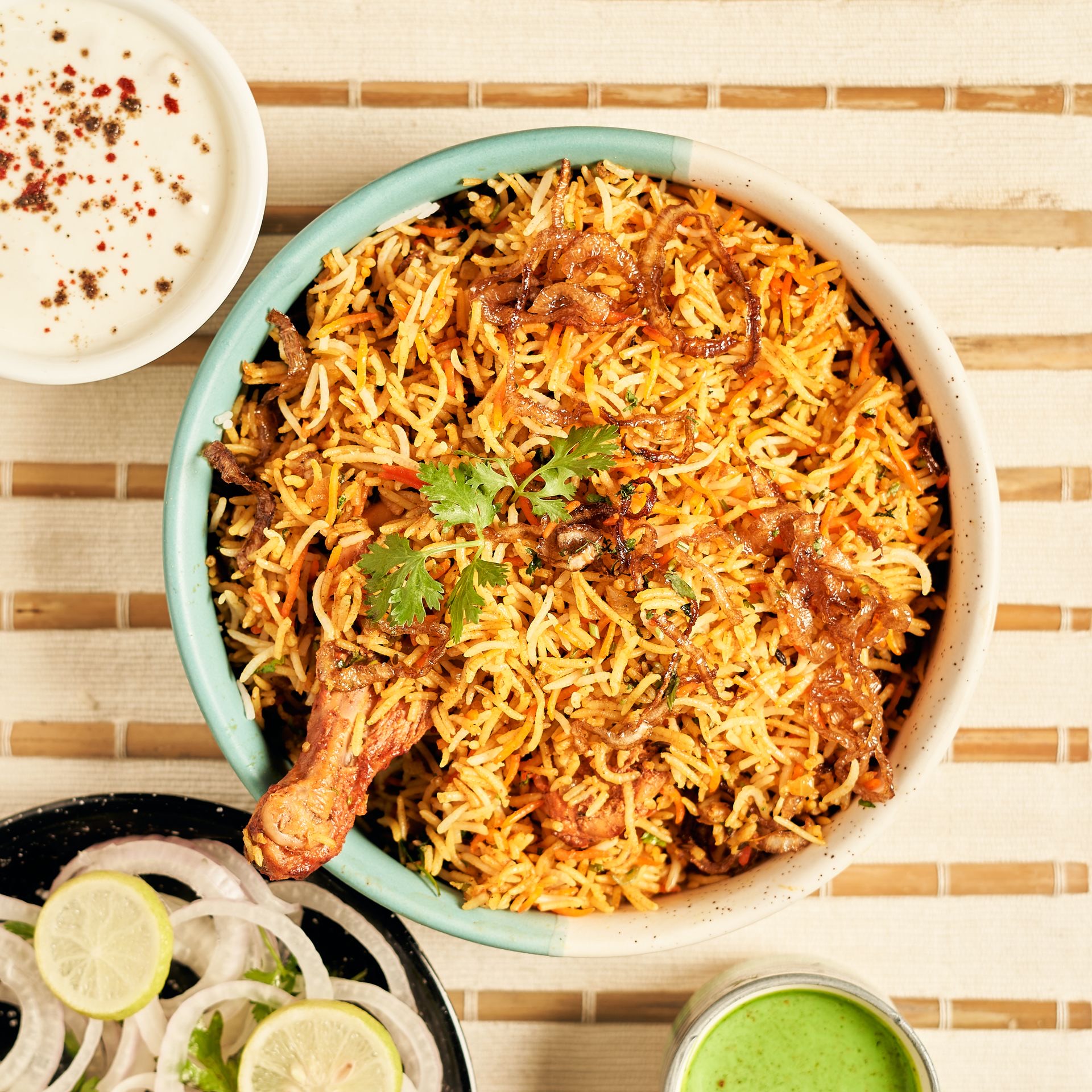 A pot of Malabar Thalassery chicken biryani garnished with fried onions, cashews and raisins.