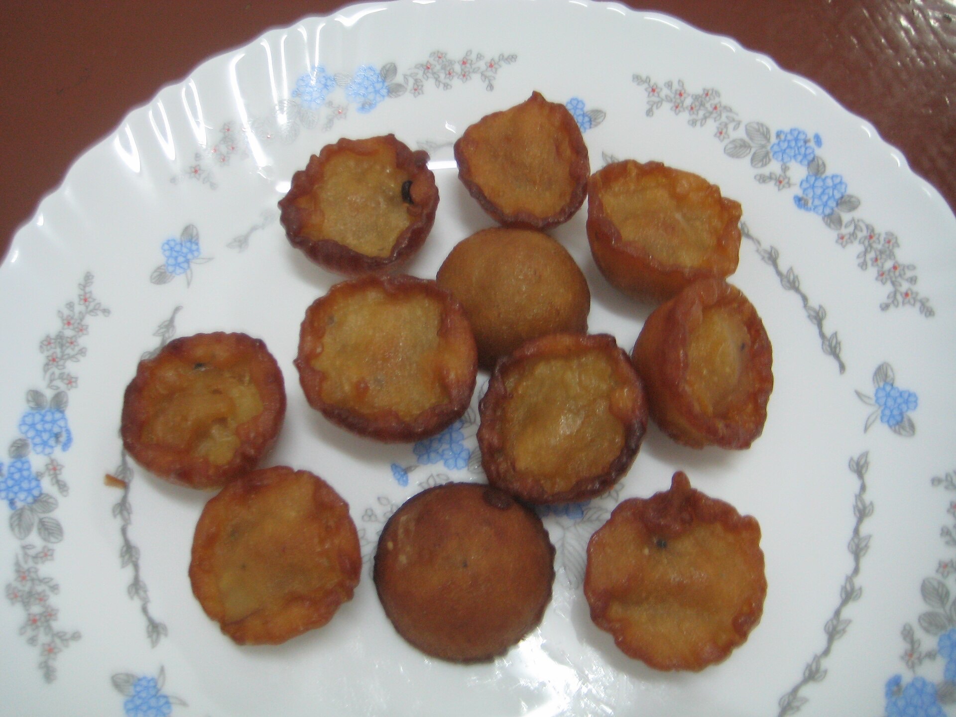 A plate of dark golden Neyyappam, small Kerala rice-and-jaggery fritters.