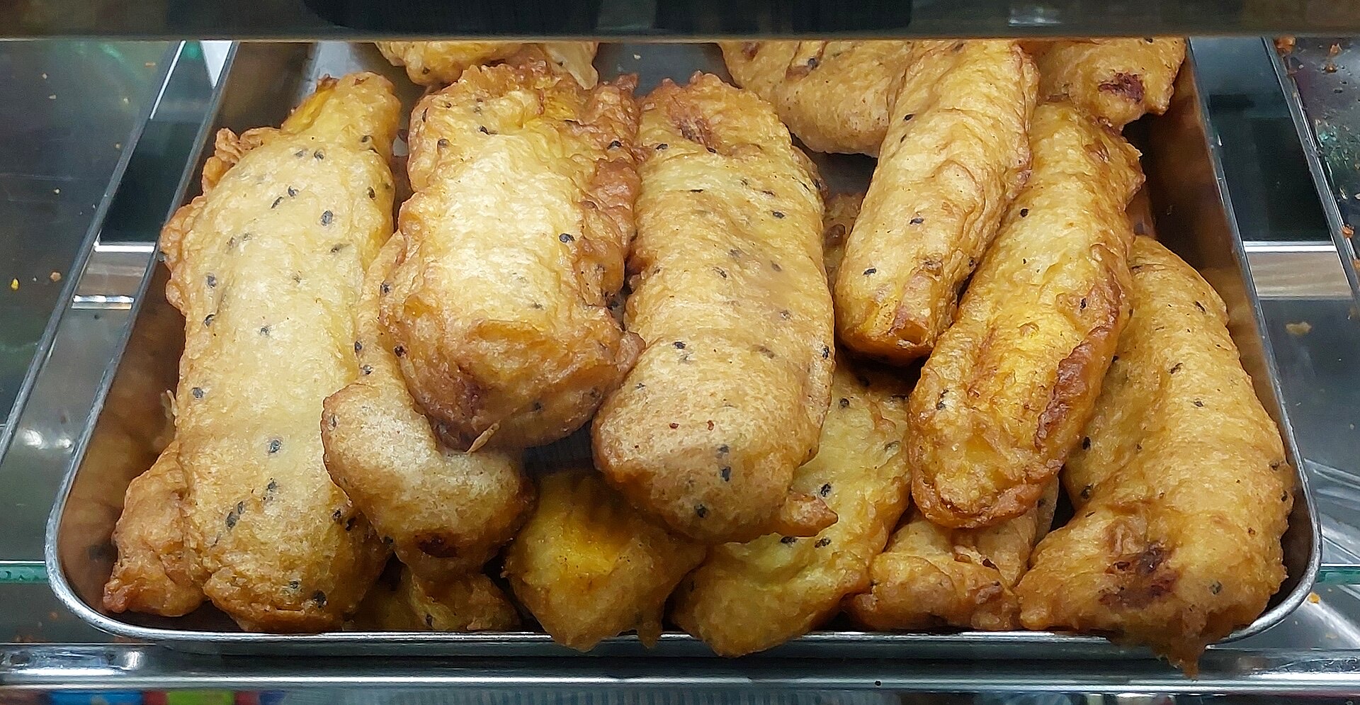Golden Pazham Pori (Kerala banana fritters) drained on paper, served with tea.