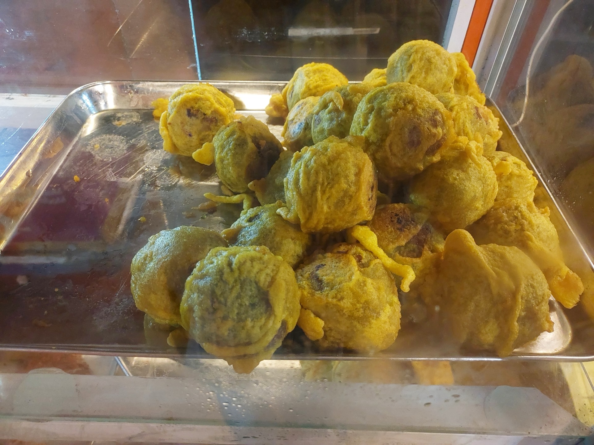 Golden Sukhiyan fritters, one broken open to show the green-gram and jaggery filling.